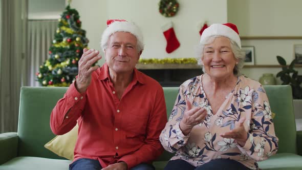 Happy caucasian senior couple in santa hats on video call at christmas time