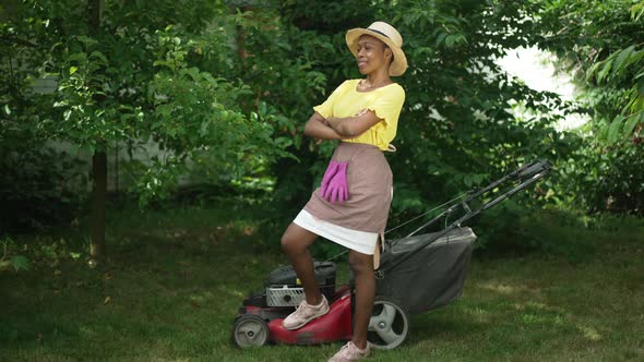 Wide Shot Confident African American Young Woman Putting Leg on Lawn Mower in Slow Motion Looking at