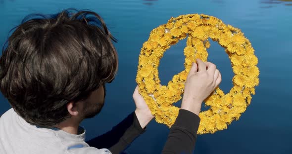 A man makes Peace sign from flowers. Concept of peace and support of Ukraine