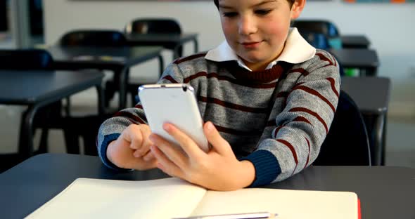 Schoolboy using mobile phone in classroom 4k