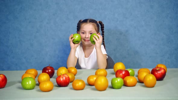 Beautiful girl with healthy food. Happy little girl sitting on the table with fruits