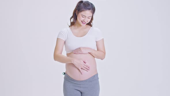 Happy Pregnant Woman standing smile and stroking big belly with love