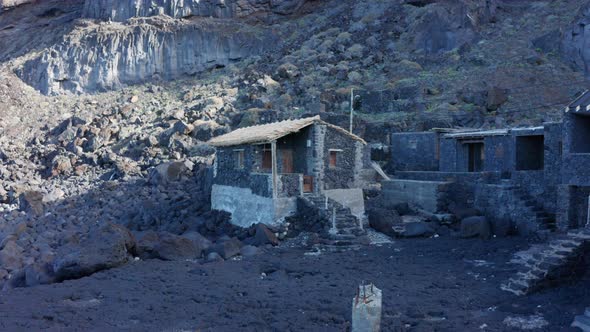 Aerial dolly walk to fishing hut black volcanic stone with thatch roof