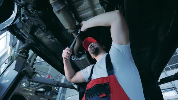 Auto Mechanic Tightens a Car Pipe From Underneath