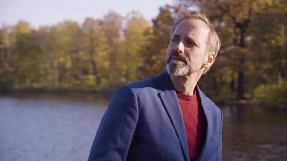 A Middleaged Handsome Caucasian Man Thinks About Something on a Bridge in a Park in Fall