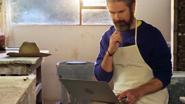 Male potter using laptop