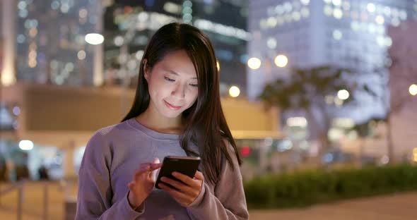 Asian Woman use of mobile phone in city at night