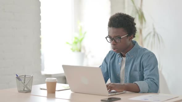 Young African Man Celebrating Success While Using Laptop