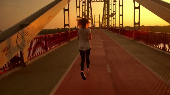 Woman Is Running Along the Bridge