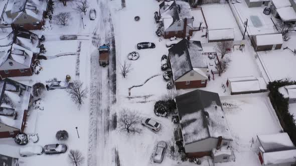 an aerial view of a suburban neighborhood in the morning, after a snow storm. The camera dolly in, t