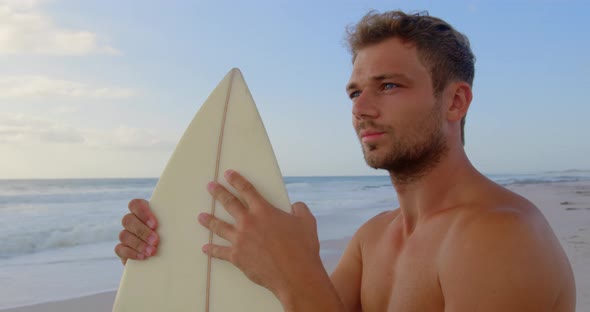 Man standing with surfboard at beach 