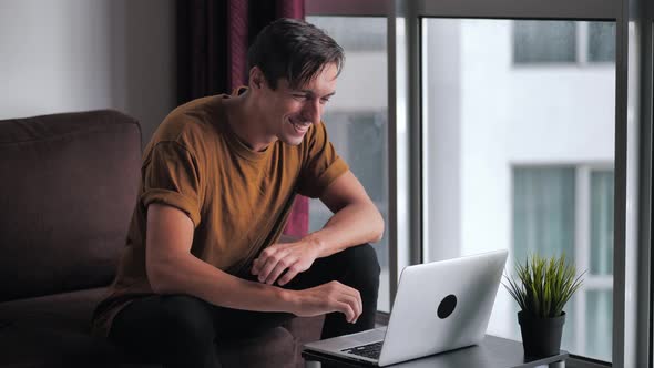 Successful Man Using Laptop Gets Surprised Then Happy and Celebrates Win While Sitting on Sofa at