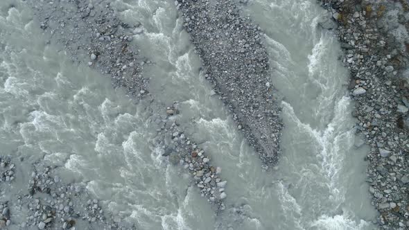 Aerial view of flowing water in river bed with pebbles, Switzerland