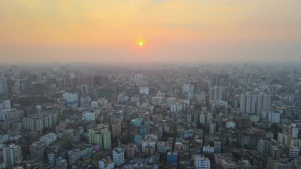 Aerial top view of populated city at sunrise with dense buildings - establishing drone descending sh