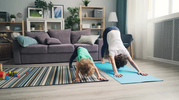 Mother and Little Son Doing Yoga Together at Home Relaxing Enjoying Activity