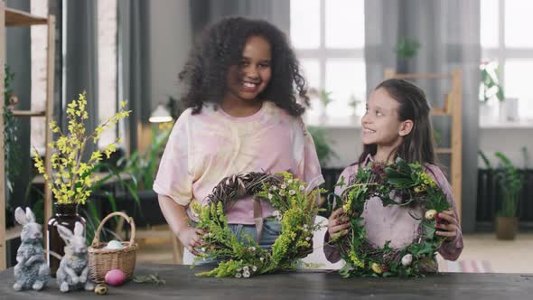 Portrait of Happy Girls with Easter Flower Wreaths