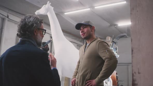 Men Discussing Giraffe Statue in Workshop