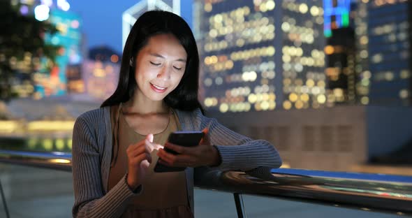 Woman looking at mobile phone in the city at night 