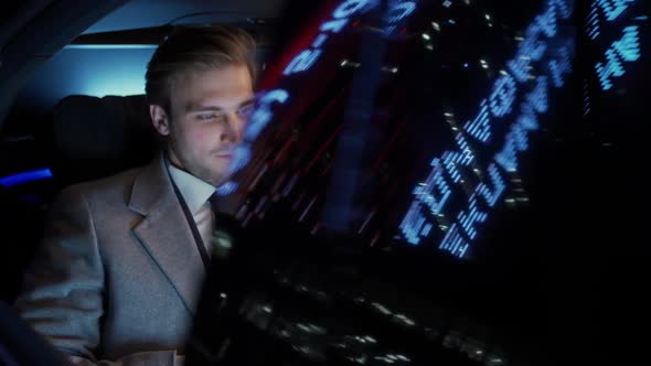 Portrait of a Young Businessman Sitting in a Moving Car Talking to the Driver and Drinking Whiskey