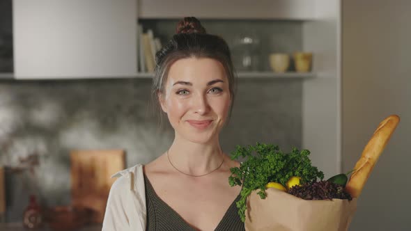 Smiling Woman Holding Grocery Bag While Standing on Kitchen