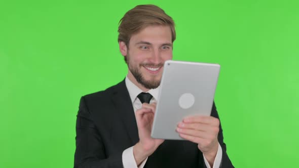 Young Businessman Celebrating Success on Tablet on Green Background