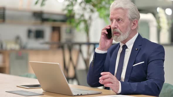 Senior Old Businessman with Laptop Talking on Smartphone