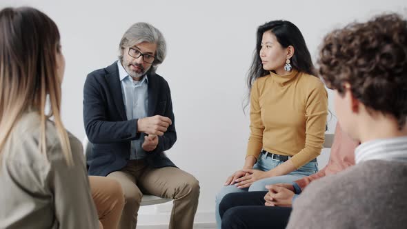 Therapist Speaking to Patients During Group Session Holding Hands Giving Help and Support