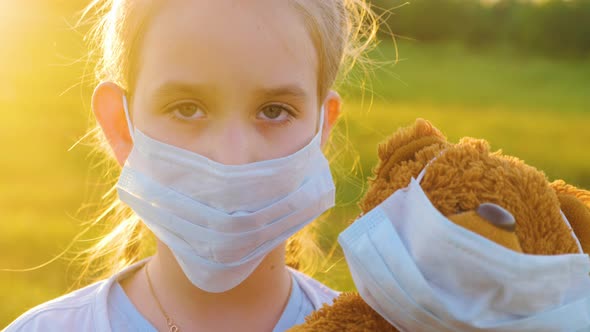 Crying Girl in Medical Protective Mask Holding a Teddy Bear at Sunset