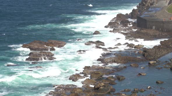 Beautiful blue ocean waves crashing the rocky shore.