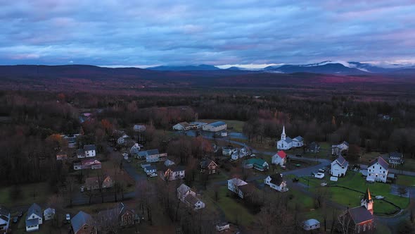 Aerial footage flying over small rural community in late fall at sunrise with misty mountains in the