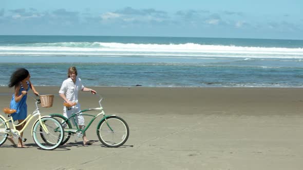 Couple walk with bicycles along coastline