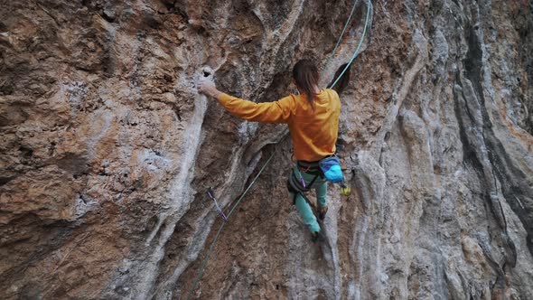 Back View of Strong Skillful Man Rock Climber Climbs Overhanging Tough Route with Rock Tufa Making