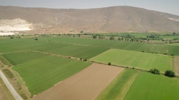 Aerial view of fields surrounded by vegetation and hills.