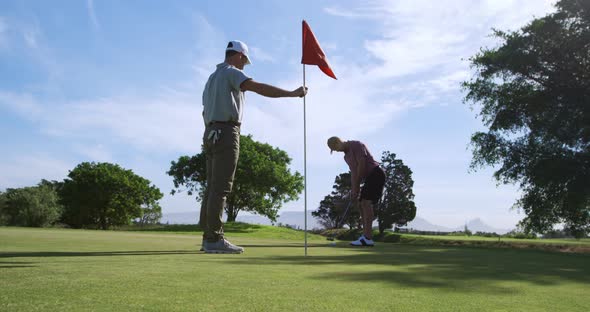 Caucasian male golfers playing on a golf course on a sunny day