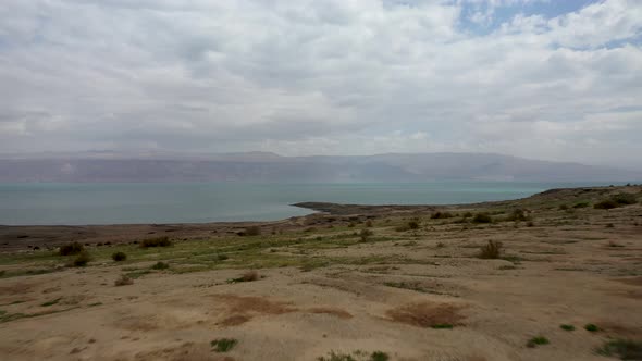 Aerial Dead sea desert greenish after rain, cloudy sky, drone shot