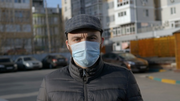 Bearded man with medical mask looking at camera.