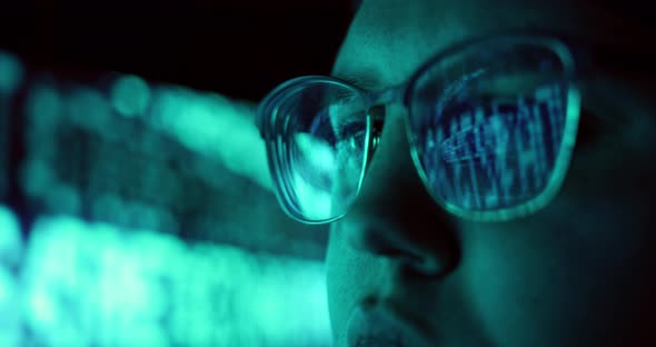 Closeup of Young Adult Female Wearing Reflective Eye Glasses Analyzing Cyber Security Code Data Work