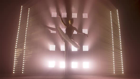 Diligent Young Graceful Ballerina Dancing Elements of Classical Ballet in the Dark with Light and