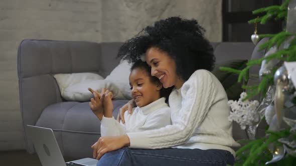 Portrait of African American Mom and Her Little Daughter Communicate By Video Call Using a Laptop