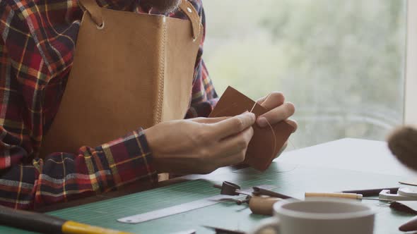 Man Making Leather Wallet at a Workshop