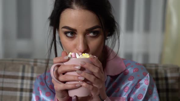 Portrait of Attractive Young Woman Drinking Hot Chocolate with Marshmallows and Watchinig Film