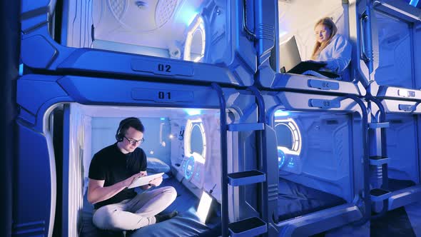 A Young Man and a Woman in Separate Capsule Hotel Rooms