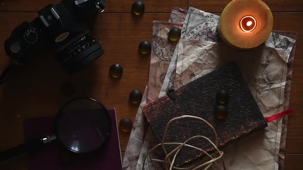 beautiful vintage background with ancient maps, a film camera, a book, a candle some stones and a ma