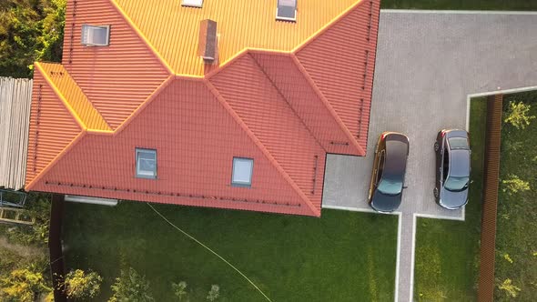 Top down aerial view of a private house with red tiled roof and spacious yard with parked two new