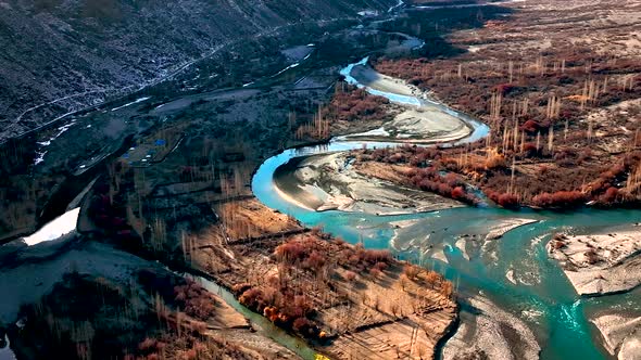 Drone Flying Over Turquoise Winding River With Sun Reflected On Surface In Valley Landscape Of Ghize