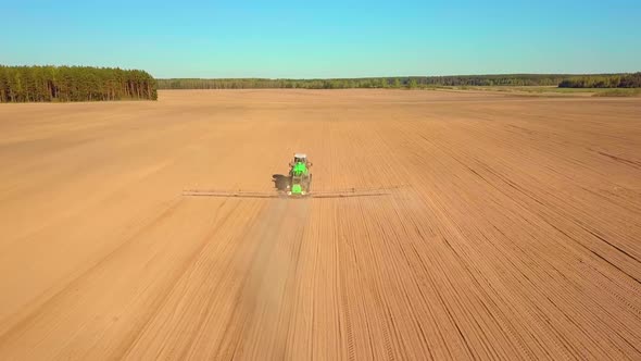 Tractor Spraying a Field with Sprayer Herbicides and Pesticides at Sunset