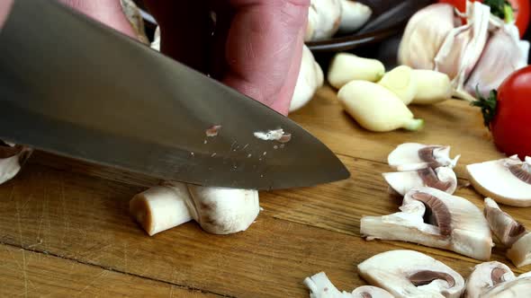 Edible Mushroom Champignon are Cutting on Wooden Kitchen Board with Sharp Knife