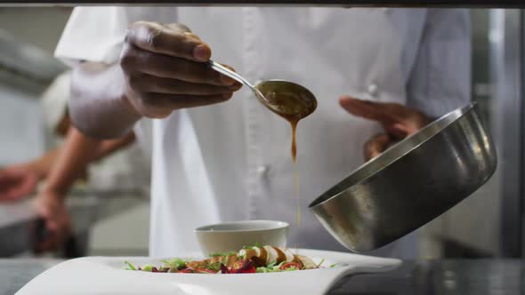 Midsection of african american frmale chef garnishing dish in restaurant kitchen