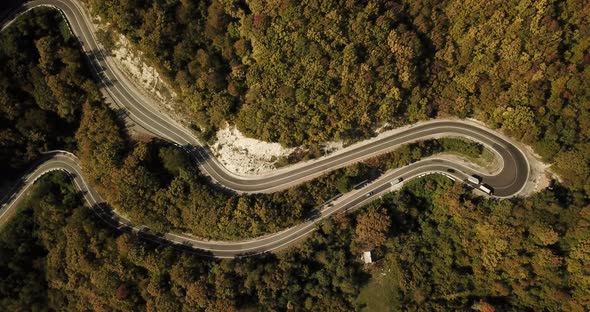 Aerial View of Car Driving Along The Winding Mountain Pass Road Through The Forest Trees. Autumn