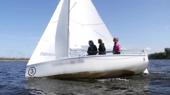 White Yacht Racing Through the Waves During a Regatta on the River. Dinamic Shot with Slow Motion